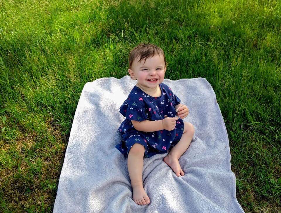 Kit sitting on a blanket smiling
